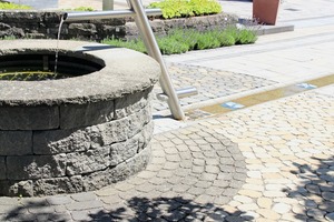  Innovative Produkte von braun-steine (v.l.n.r.): Arena-Pflaster rund um einen Brunnen aus Santuro-Steinen, Para Verde-Mauer sowie Ensemble aus einer Mauer aus Santuro-Steinen, einer zweiten Mauer aus Cult Long-Line-Steinen und aus Mahora-Holzstruktur-Lamellendielen 