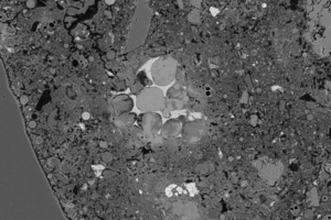  SEM micrograph of an R concrete (C25/30); bright section in the center of the image = unhydrated clinker phases of the cement in the recycled aggregates made from crushed concrete 