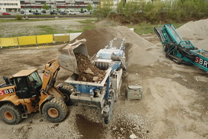  An excavator fills the impact crusher at the nearby temporary storage facility 