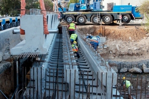  Workers insert rebar through sleeves situated in the beams’ lower web sections  
