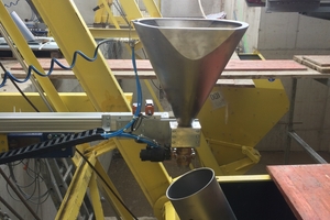  A conveying vessel discharging the color pigments into the respective elevator bucket 