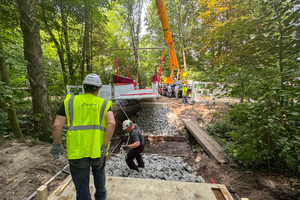  Fig. 1: Installation of the CPC modular bridge in Oldenburg: A mobile crane is lifting the pre-assembled bridge element made of prestressed carbon-reinforced concrete over the railway embankment ditch in Drielake  