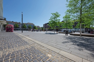  The tactile guidance system for the blind formally serves as a caesura between the gray Vajo paving slabs and the cobblestone pavement at the fringe area of the square  