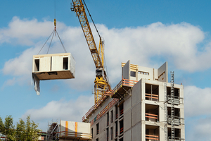  Fig. 2: A prefabricated room module is lifted by crane onto the construction site  