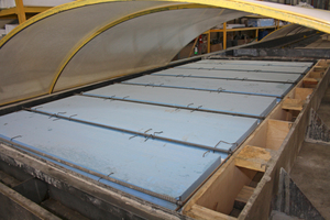  Steel reinforcement and insulating material have been placed on the production tables. In the following step, a spreader pours the concrete onto the entire table area enclosed by the mold elements  
