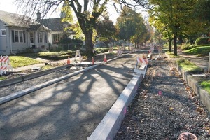  Fig. 6 The drainage blanket base runs under the curbs across the width of the street. Geotextile was placed over the top of the drainage blanket in the asphalt center strip and dense-graded base compacted into place as shown here. Temporary driveways built with base and plywood allowed access to residents’ driveways.  