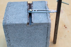  A modular block of lightweight concrete with built-in anchorage components is fixed to anchor channels with a brick tie 