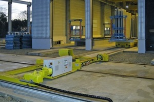  A three-rail platform car (in the foreground) receives the lifting cars bearing the double walls (in the background)<br /> 