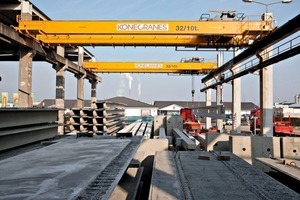  This is how it looks like behind the narrow black curtain: the two cranes are equipped with specially designed protective gear for moving precast elements through the curtain to the outdoor storage area 