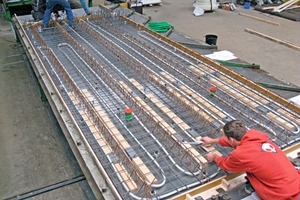  In die vorgefertigte untere Sandwichschale einer Ceiltec A-Decke werden im Werk Verdrängungskörper und TGA-Leitungen eingelegt 