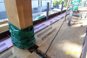  → 2 Detailed view of the timber-concrete composite floor: LSL elements with some inserted WCC shear connectors visible on the top side. The insulation panels have also been laid. In the foreground, the image clearly shows the stud shear connectors mounted on the steel beams, which contribute to creating a biaxially restrained floor structure after concrete pouring  